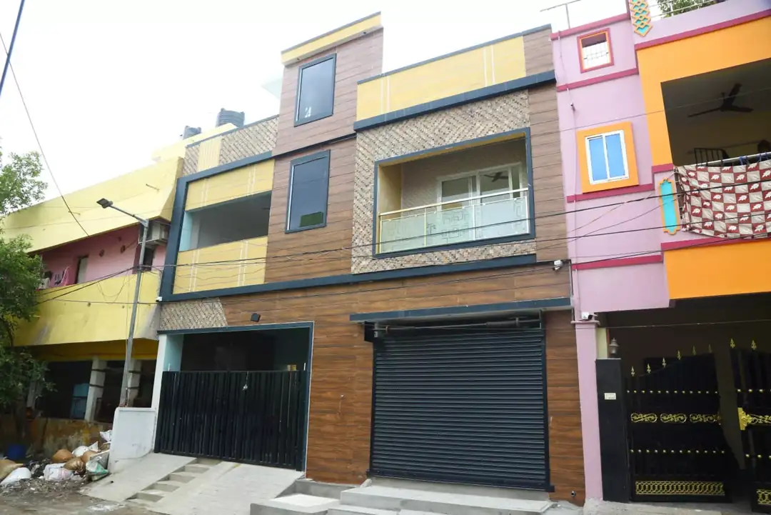 Street view of the Kolathur building with wood-finish cladding and mustard accent panels